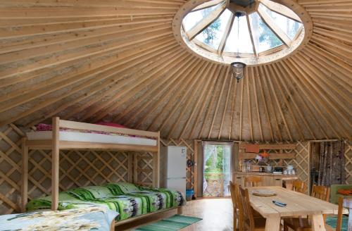 Habitación con techo de madera, cama y mesa. en Yurtos, en Gaugariai