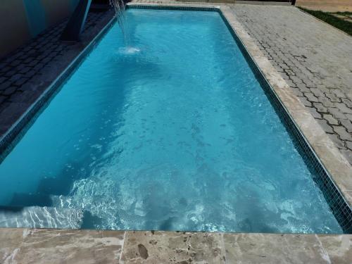 a swimming pool with blue water in it at Refúgio Guarajuba, 50m da Praia, Piscina, Recarga EV, área gourmet, churrasqueira in Camaçari