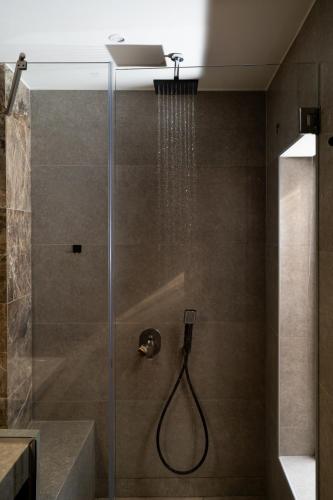 a shower with a glass door with a shower head at The Mall Luxury Suites in Nikiti