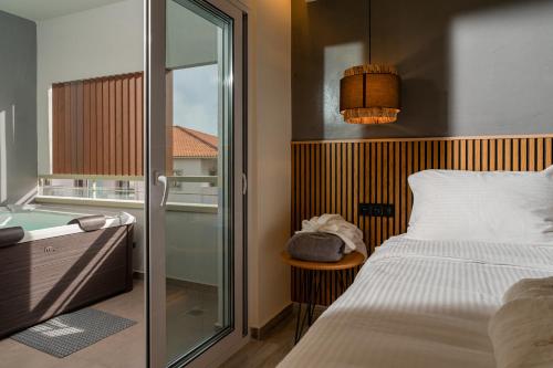 a bedroom with a bed and a tub and a window at The Mall Luxury Suites in Nikiti