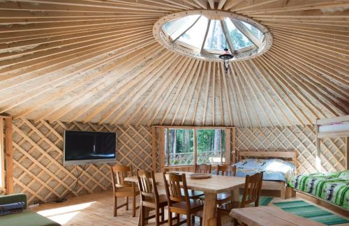 a room with a wooden ceiling with a table and a tv at Yurtos in Gaugariai