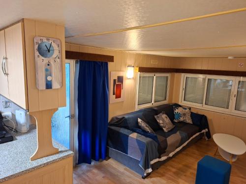 a living room with a couch and a clock at Mobile home style maisonnette de vacance in Méjannes-le-Clap