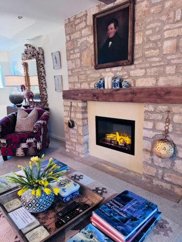 a living room with a fireplace with a painting on the wall at Little Campden House in Chipping Campden