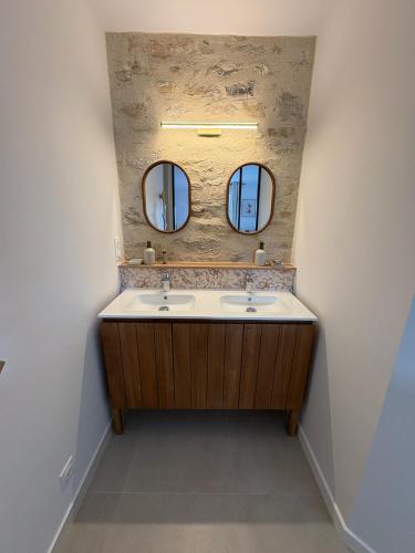 a bathroom with two sinks and two mirrors at Chambre d'hôtes Camélia in Saint-Lyphard