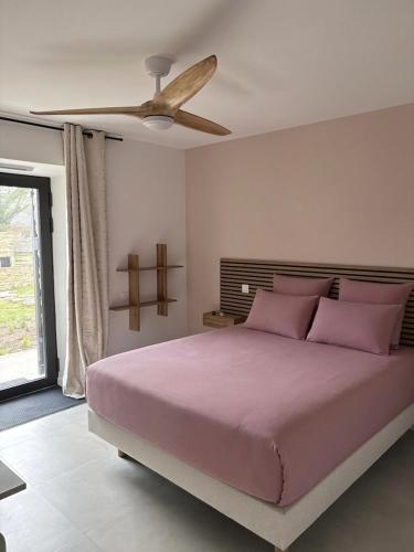 a bedroom with a bed with pink pillows and a ceiling fan at Chambre d'hôtes Camélia in Saint-Lyphard