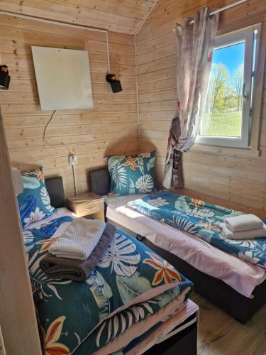two beds in a room with a window at Chatki przy Marinie in Wapnica