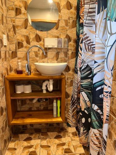 ein Badezimmer mit Waschbecken und einer Steinwand in der Unterkunft Mareva Kore in Avarua