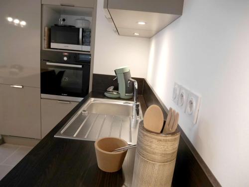 une petite cuisine avec un évier et un micro-ondes dans l'établissement Le janua - Accort, à Annecy