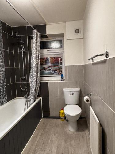 a bathroom with a toilet and a bath tub at Emerald Room - shared bathroom in Ponders End