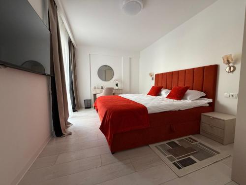 a bedroom with a large red bed with red pillows at IDDA Concept 1 in Târgu-Mureş