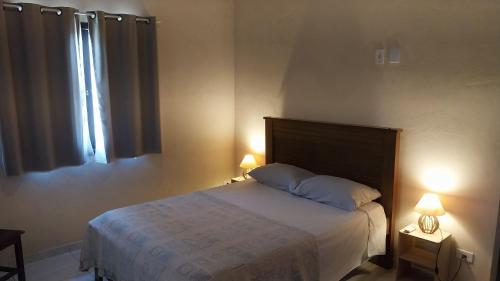 a bedroom with a bed with two lamps and a window at Sobrado entrada de Paraty in Paraty