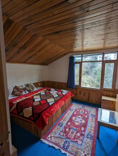 a bedroom with a bed with a rug and a window at Casa Nova in Manāli