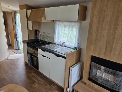 a small kitchen with a sink and a stove at Manderley Caravan in Newquay Bay Resort