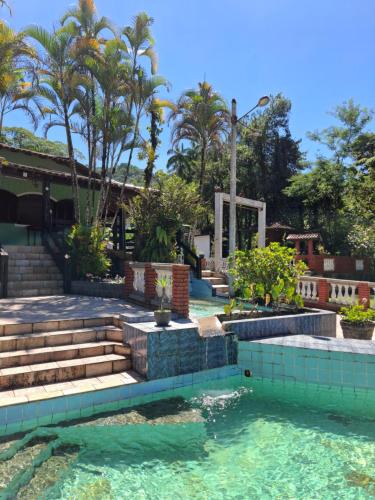 a swimming pool in a house with trees and water at Pousada Luar de Penedo in Penedo