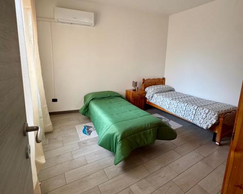 a room with two beds and a green blanket at Casa Sandalia in Villacidro