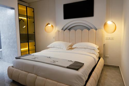 a bedroom with a large white bed with a flat screen tv at 18 On OniX - World Class in Four Ways