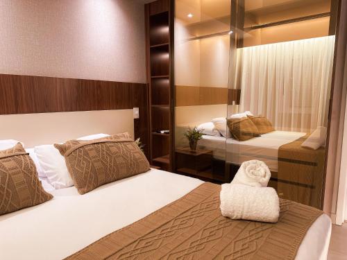 a bedroom with two beds and a mirror at Loft Prime Ribeirão Apogeo in Ribeirão Preto