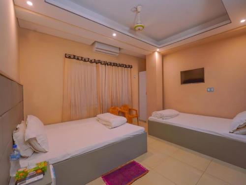 ein Schlafzimmer mit zwei Betten, einem Tisch und Stühlen in der Unterkunft Sylhet Hotel Grand Usman in Sylhet