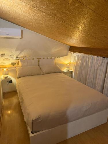 a bedroom with a large white bed with two lamps at Casa Dani - terrazza relax, parcheggio gratuito e comfort a due passi da Oneglia in Imperia