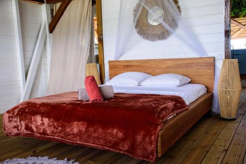 a bed with a red blanket and white pillows on it at Tootila in Sainte-Rose