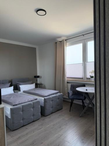 a bedroom with two beds and a table and window at Gästehaus Orchidee in Hoya