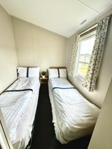 two beds in a small room with a window at Atlantic 63 in Bude