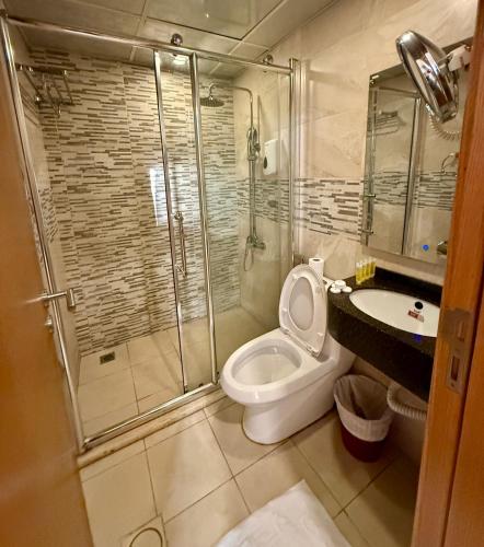 a bathroom with a shower and a toilet and a sink at Jawheret S Hotel Suite in Amman