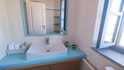a bathroom with a white sink and a mirror at Cycladic Stone House with Pool & Sunset Views in Gialiskari