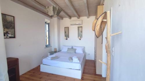 a bedroom with a white bed in a room at Cycladic Stone House with Pool & Sunset Views in Gialiskari