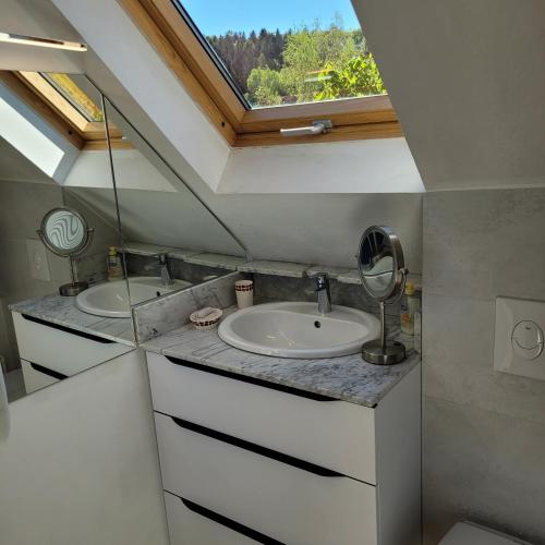 a bathroom with two sinks and a window at La Colline aux Oiseaux in Tieffenbach