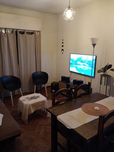 a living room with a tv and a table and chairs at Cómodo, bien ubicado y con host multilingüe in Montevideo