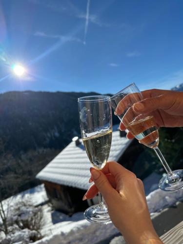 two people holding up glasses of wine in front of a view at Chalet cosy avec vue montagne proche La Clusaz & Le Grand-Bornand in Saint-Jean-de-Sixt