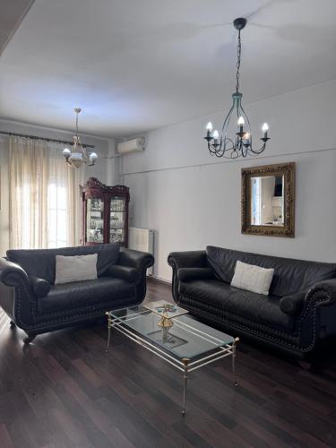 a living room with two black couches and a glass table at SugarV Home in Kilkis