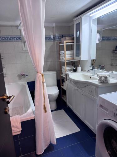 a bathroom with a sink and a toilet and a shower curtain at SugarV Home in Kilkis