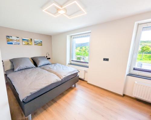 a bedroom with a bed and two windows at Ferienwohnung MoselVino in Lieser