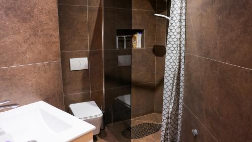 a bathroom with a shower with a toilet and a sink at Enzo's Apartments Prishtina in Prishtinë
