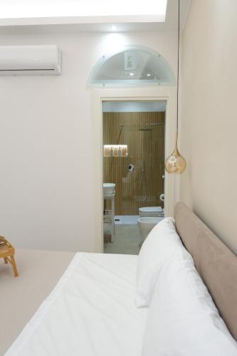 a white bedroom with a bed and a bathroom at Dimora Don Ferdinando in Naples