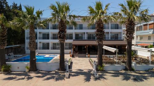 a hotel with palm trees in front of a building at Tunan Motel in Ayvalık