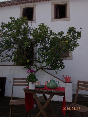 a table with a tree on it next to a house at Casa do Castelo - Óbidos in Óbidos