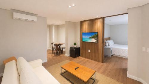 a living room with a couch and a bed and a table at Hotel Praia Brava in Florianópolis