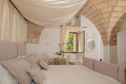 a bedroom with a white bed and a window at Masseria Pagliamonte in San Vito dei Normanni