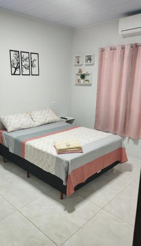 a bedroom with a bed and a pink curtain at Quarto Casal Com AR Condicionado e Banheiro Privativo in Guaíra