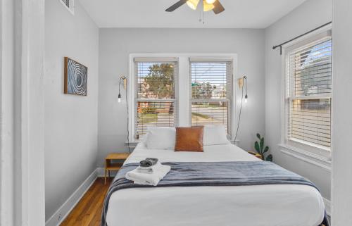 a bedroom with a large white bed with two windows at Natural Sabbatical 1 Bedroom Apartment in Dallas
