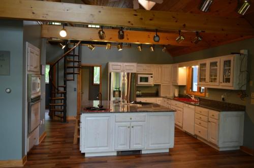 a large kitchen with white cabinets and a staircase at Shimmering Cove Retreat in Naples