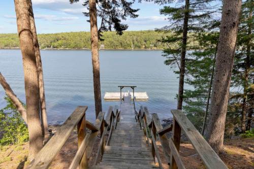 a wooden boardwalk leading to a dock on a lake at Shimmering River Retreat in Edgecomb