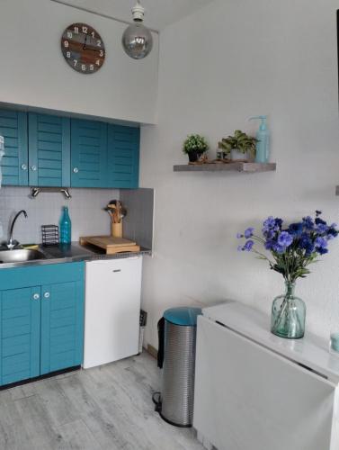 a kitchen with blue cabinets and a vase of flowers at Le Cocon Bleu in Ustou