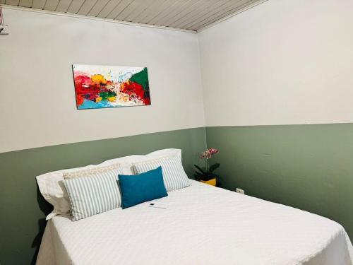 a bedroom with a white bed with a painting on the wall at Casa Aconchego 2, Self Check-in in Presidente Prudente