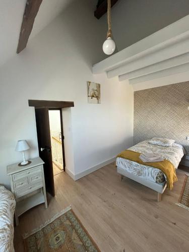 a bedroom with two beds and a night stand and a table at Au petit soulier de Puisaye in Treigny