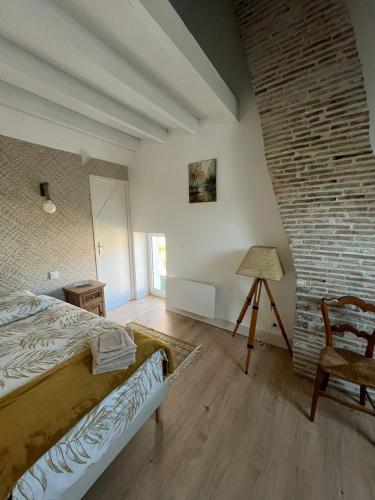 a bedroom with a bed and a brick wall at Au petit soulier de Puisaye in Treigny