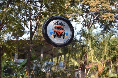 a sign hanging from a tree with a bus at Dreams Hostel in Vagator